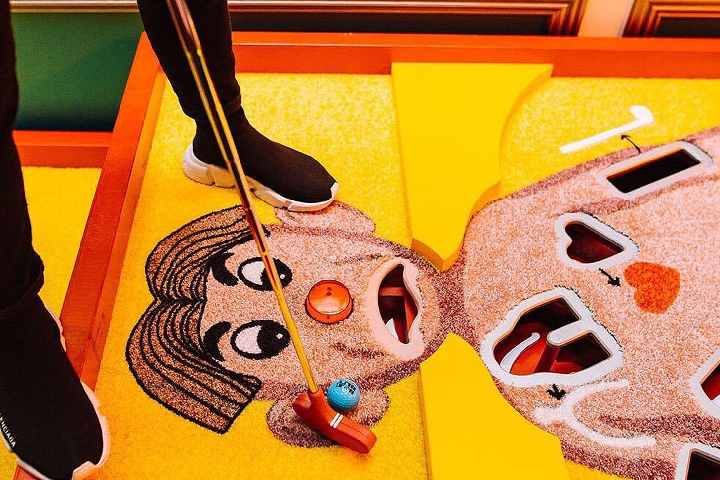 A person putts a ball on an Operation man's face.